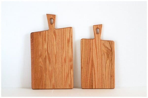 Two wooden cutting boards with handle holes, crafted from natural wood.